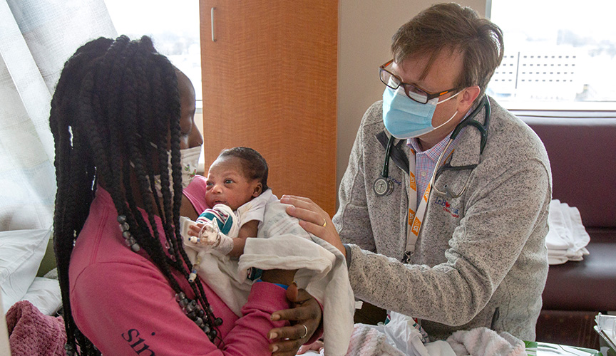 Doctor examines patient held by parent.